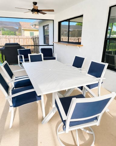 Covered patio with white dining table, blue and white chairs, ceiling fan, and view of backyard
