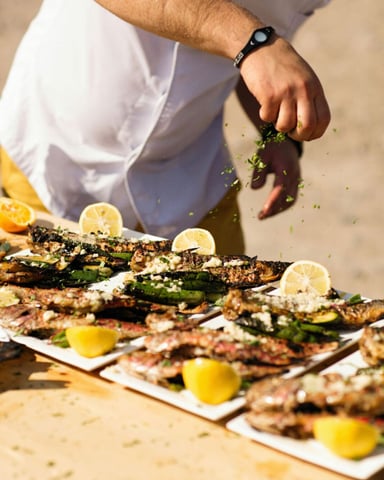 Chef finishing grilled dishes with herbs and lemon